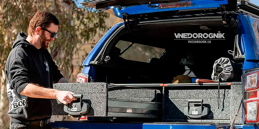 Happy man easily opening a fully loaded drawer in his SUV, showing convenience and joy of organized travel space.