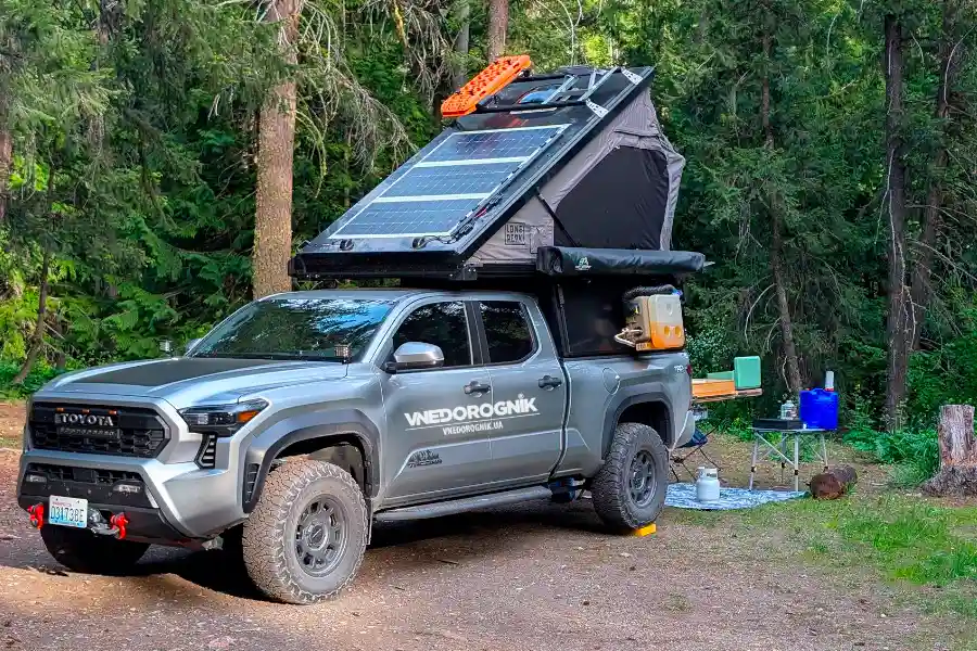 A Toyota SUV with a truck camper is parked in the forest. An atmosphere of peace, nature, and freedom — the perfect photo for topics on road trips, camping, and outdoor recreation.